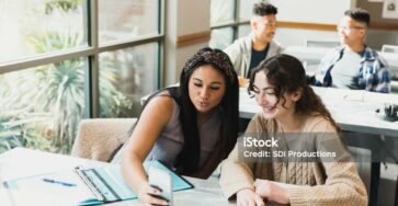 Un groupe diversifié de jeunes entrepreneurs dans un pays en développement, travaillant ensemble dans un espace de bureau moderne. Ils brainstorment autour d'une table avec des ordinateurs portables, des carnets et un tableau blanc, illustrant l'innovation, la collaboration et la transformation économique.